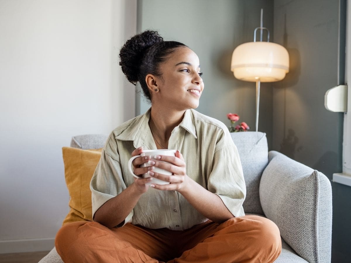 A woman relaxing with a warm drink at home, reflecting calm and stress relief—benefits commonly associated with holistic care such as acupuncture.