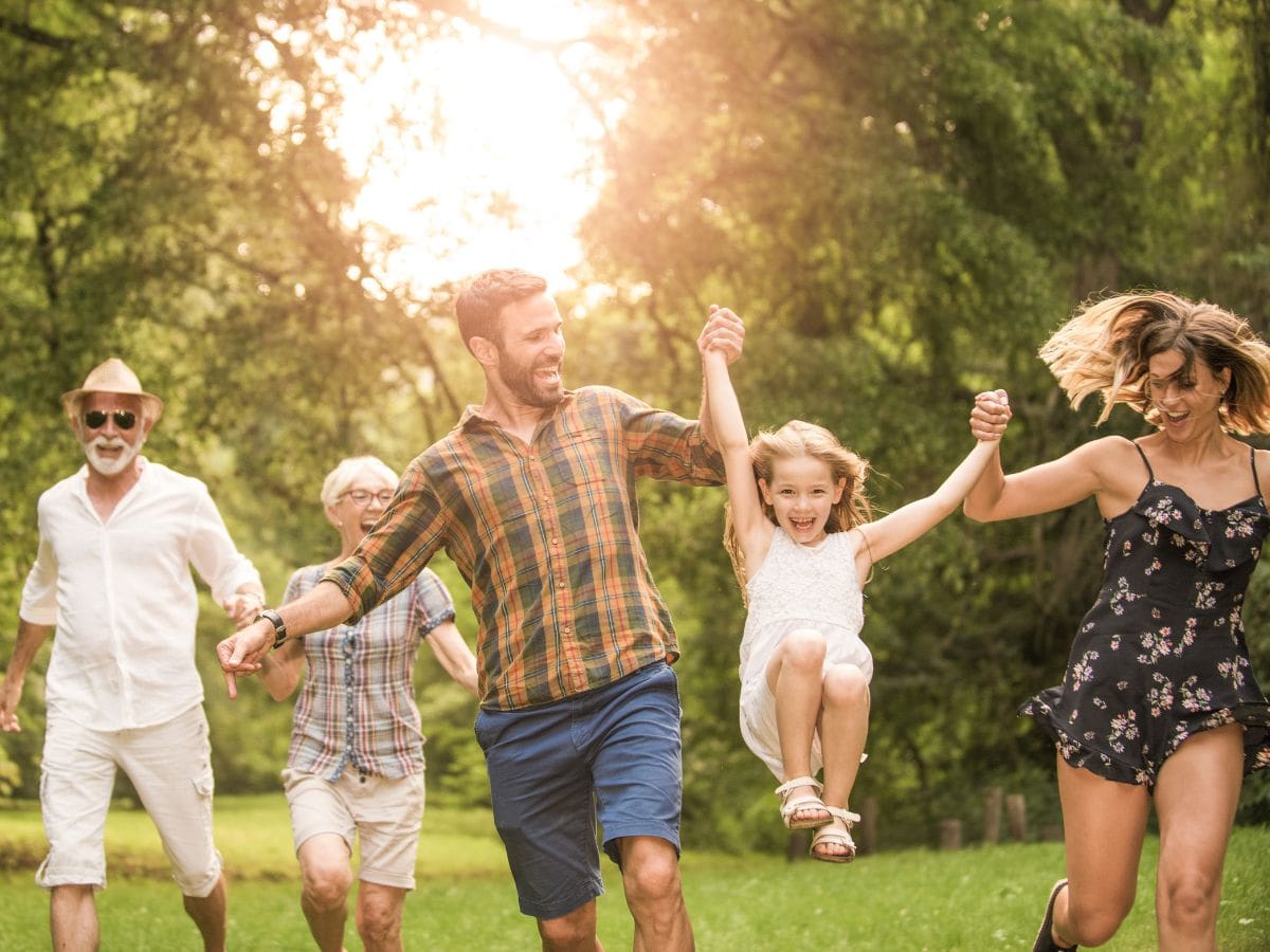 Multi-generational family playing joyfully outdoors symbolizing health, vitality, and energy benefits from acupuncture therapy.