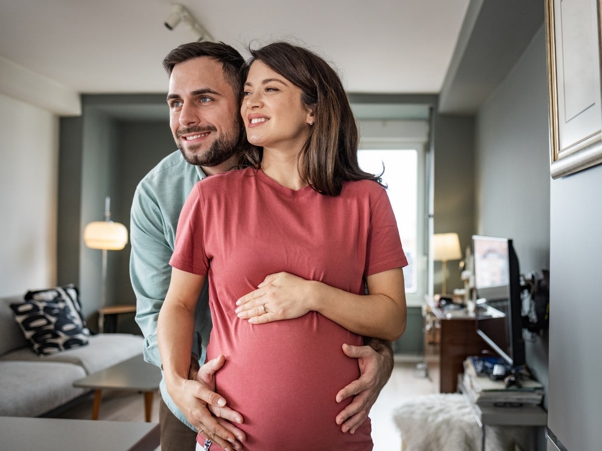 Expectant couple embracing and smiling, representing the benefits of acupuncture for fertility and reproductive wellness.