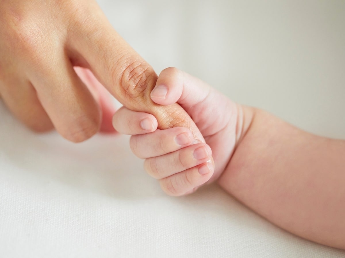 Newborn baby gently holding an adult’s finger, symbolizing the joy and success of fertility treatments and new beginnings.