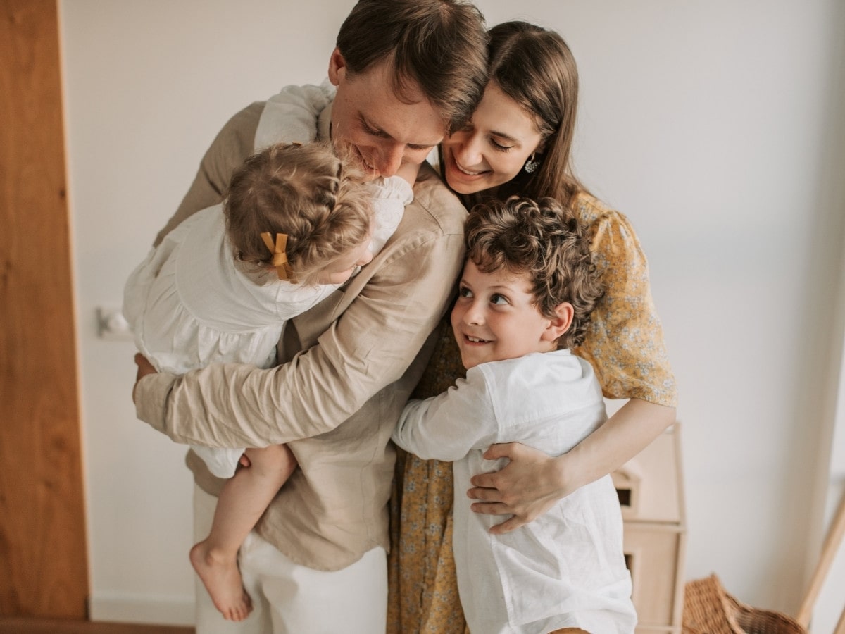 Young family with two children hugging and smiling together, reflecting vitality and well-being from acupuncture treatments.