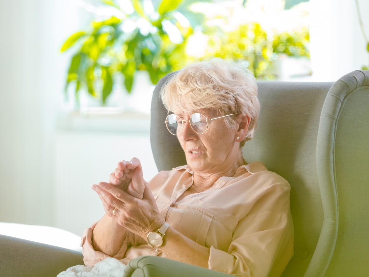 Older woman experiencing numbness or discomfort in her hand, a common sign of peripheral neuropathy.