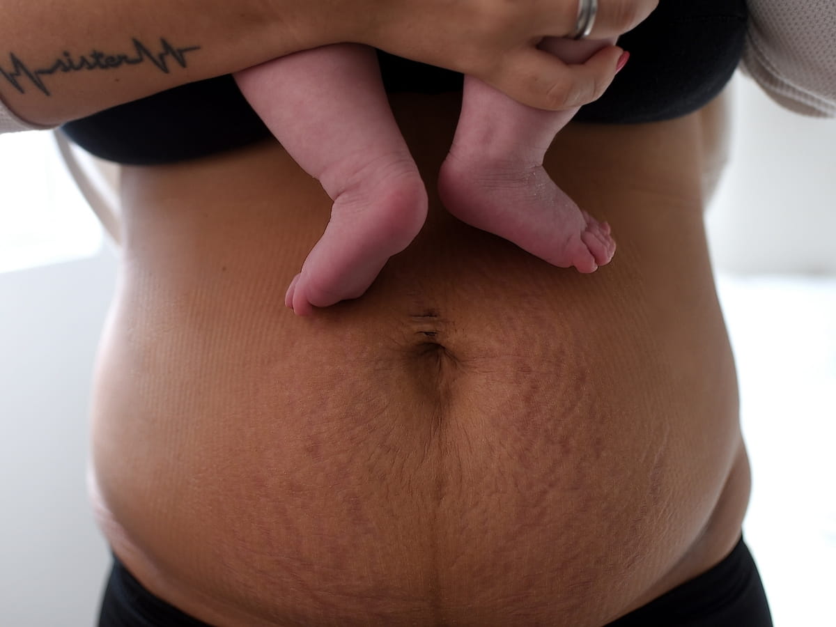 Mother holding a newborn during postpartum care and recovery.